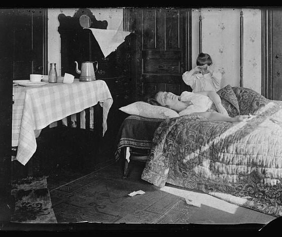 An unwell woman lying in her bed with a young child